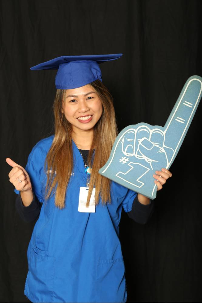 nursing student holds up foam finger with thumbs up for a picture